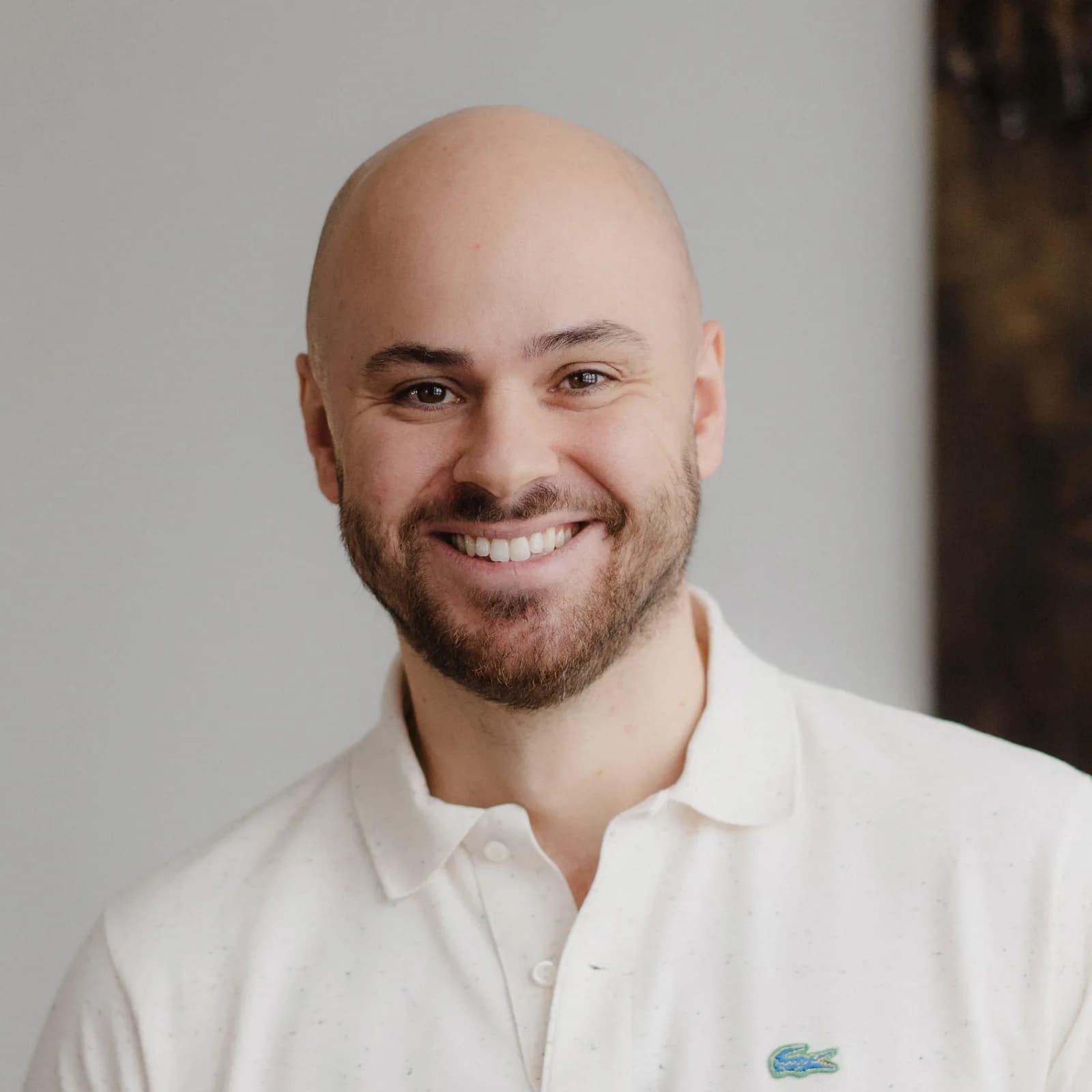 Anil Altinbasak guckt freundlich in die Kamera. Er steht in seinem Büro und trägt ein helles Poloshirt.